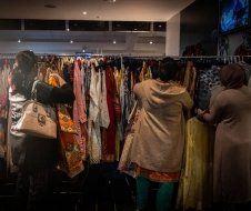 A group of women are looking at clothes in a store.