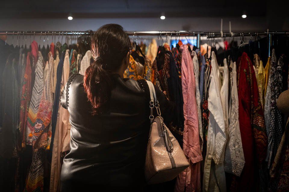 A woman is looking at clothes on a rack in a store.