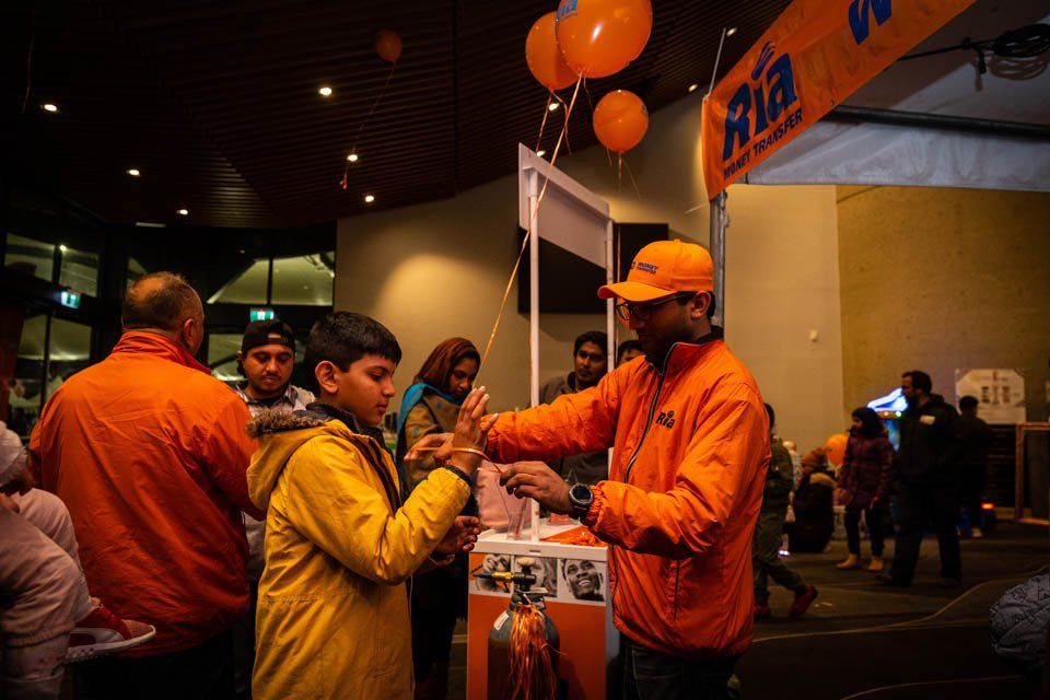 A man in an orange jacket is talking to a boy in a yellow jacket.