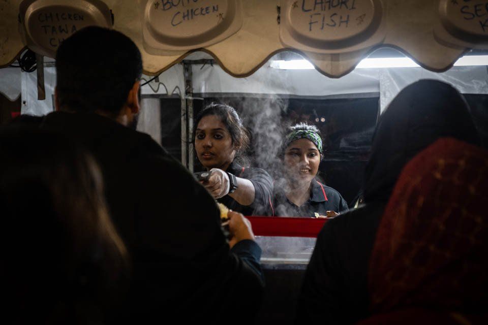 A group of people are standing in line at a food stand.