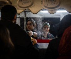 A woman is serving food to a group of people at a food stand.