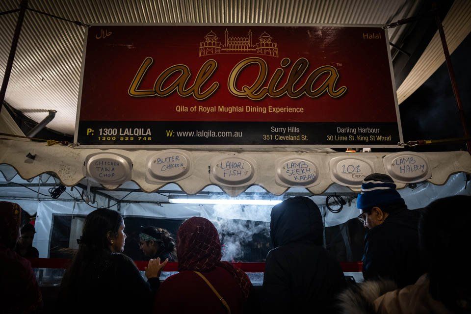 A group of people are standing in line at a food stand.