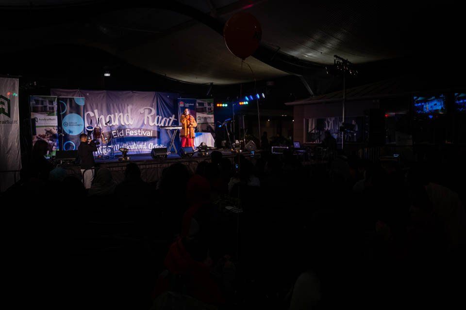 A man is standing on a stage in front of a crowd at a concert.