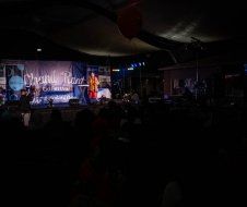A group of people are standing on a stage in a dark room.