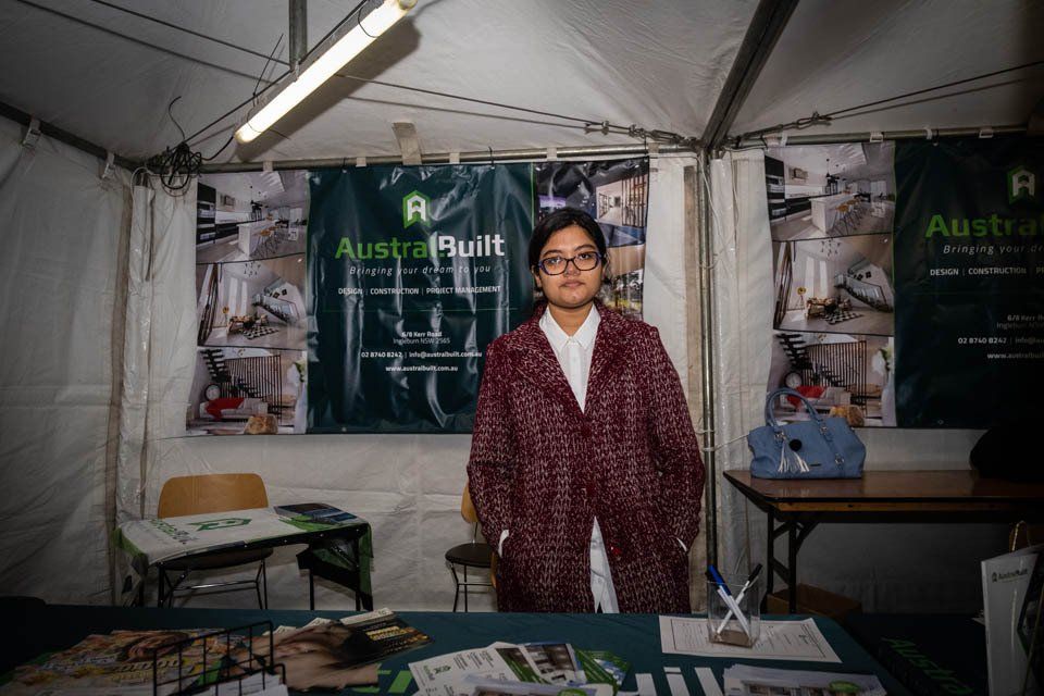 A woman is standing in front of a table in a tent.