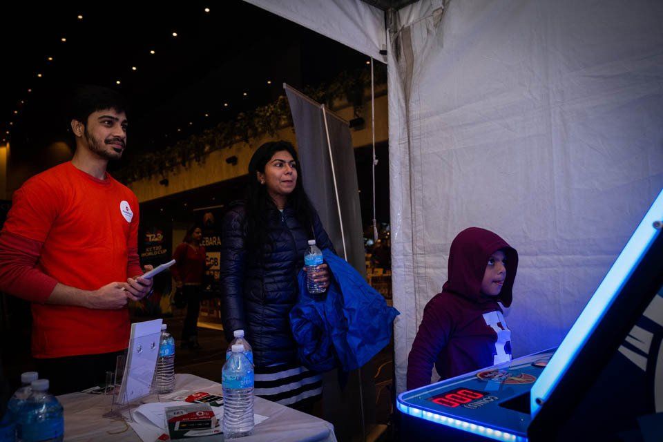 A man and a woman are standing next to a child playing a video game.