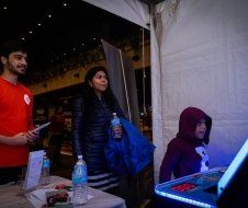 A group of people are standing around a table under a tent.