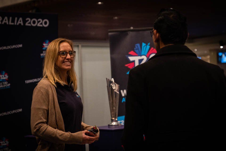 A woman is talking to a man in front of a trophy.