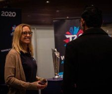A woman is talking to a man in front of a trophy.