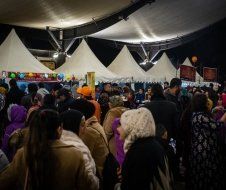 A crowd of people are gathered under a tent at a festival.