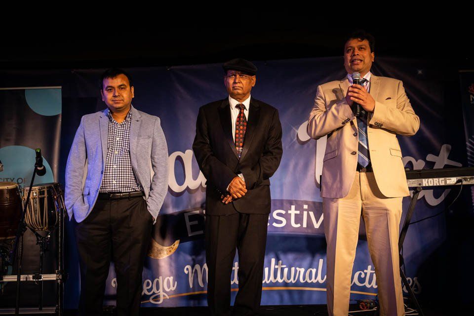 Three men in suits and ties are standing next to each other on a stage.