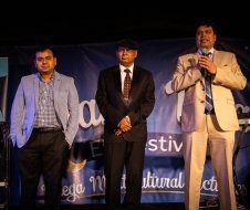 Three men in suits and ties are standing next to each other on a stage.
