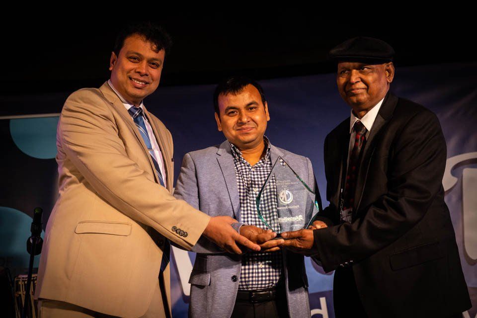 Three men are standing next to each other holding a trophy.