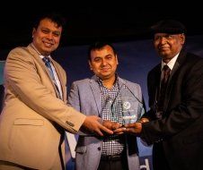 Three men in suits are standing next to each other holding a trophy.