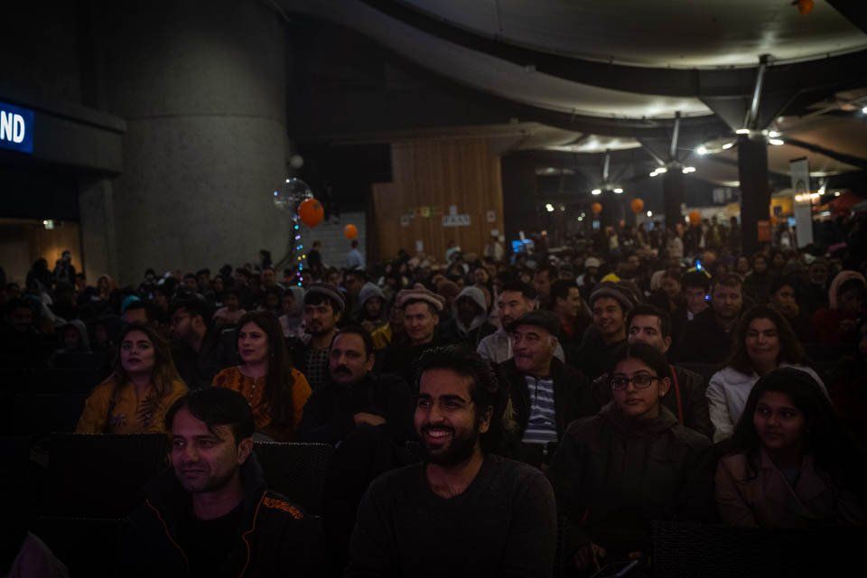 A large group of people are sitting in a dark room watching a movie.