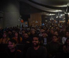 A large group of people are sitting in a dark room watching a movie.