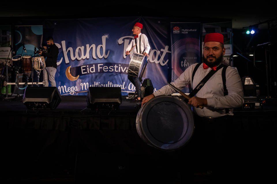 A man is playing a drum on a stage at a festival.
