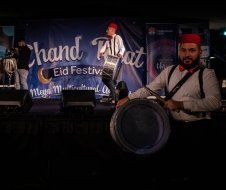 A man is standing on a stage holding a drum.