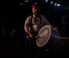 A man is playing a drum in a dark room.