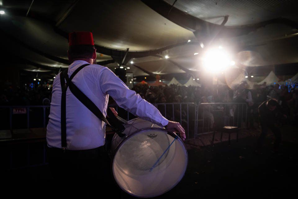 A man is playing a drum in front of a crowd.