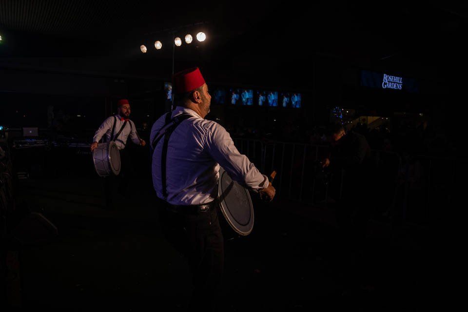 Two men are playing drums in a dark room.