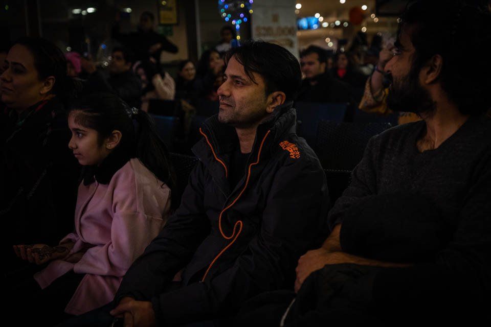 A group of people are sitting in a dark room watching a movie.