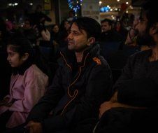 A group of people are sitting in a dark room watching a movie.