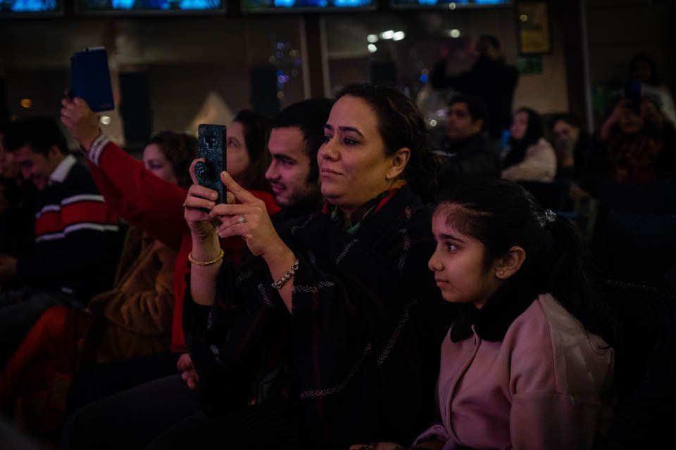 A woman is taking a picture of a girl with her cell phone.