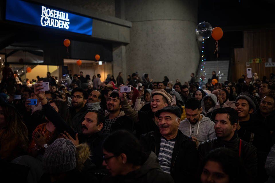 A large group of people are standing in front of a sign that says rosehill gardens.