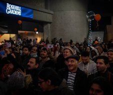 A crowd of people are gathered in front of a sign that says rosehill gardens.