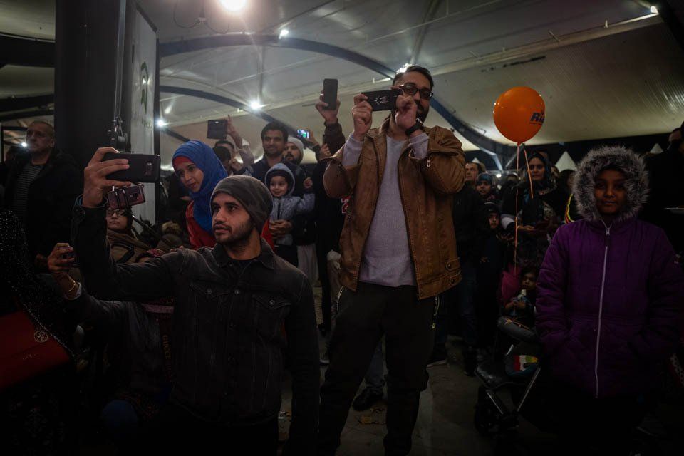 A man is taking a selfie in front of a crowd of people.