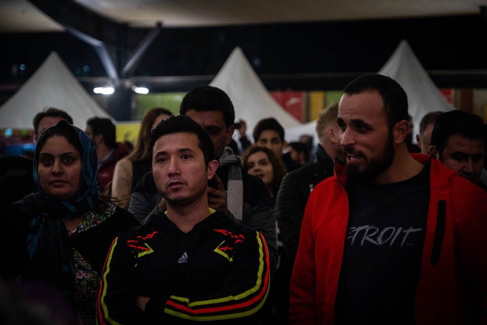 A group of people are standing in a room with tents in the background.