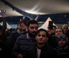 A group of people are standing in a room looking at their phones.