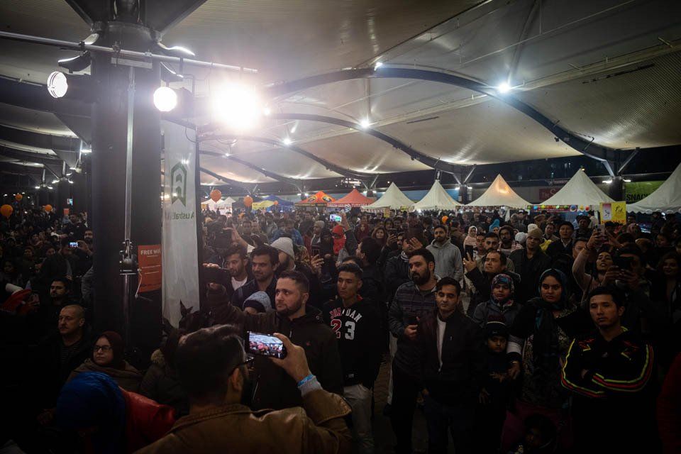 A man is taking a picture of a crowd of people at a festival.