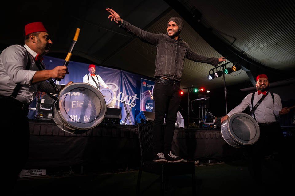 A group of men are playing drums and dancing on a stage.