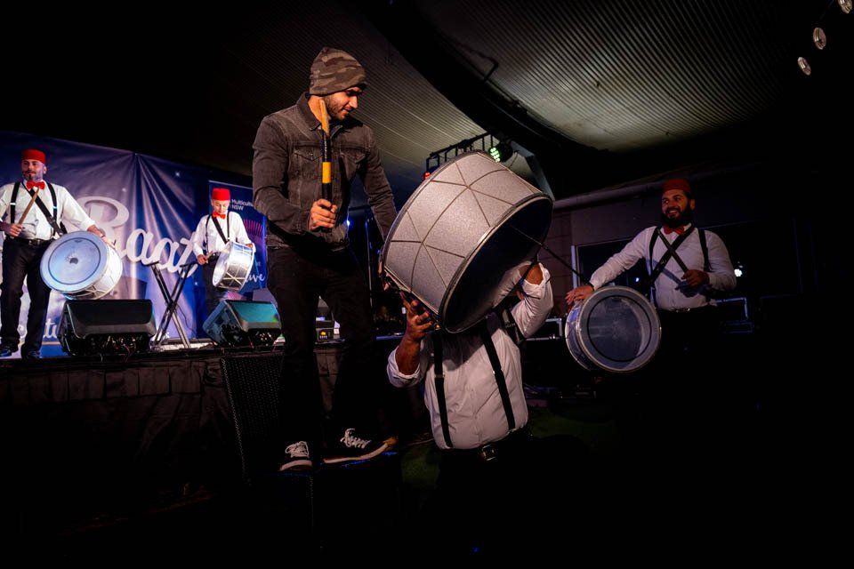 A man is standing on a stage holding a drum and singing into a microphone.