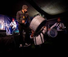 A man is standing on a stage holding a drum.