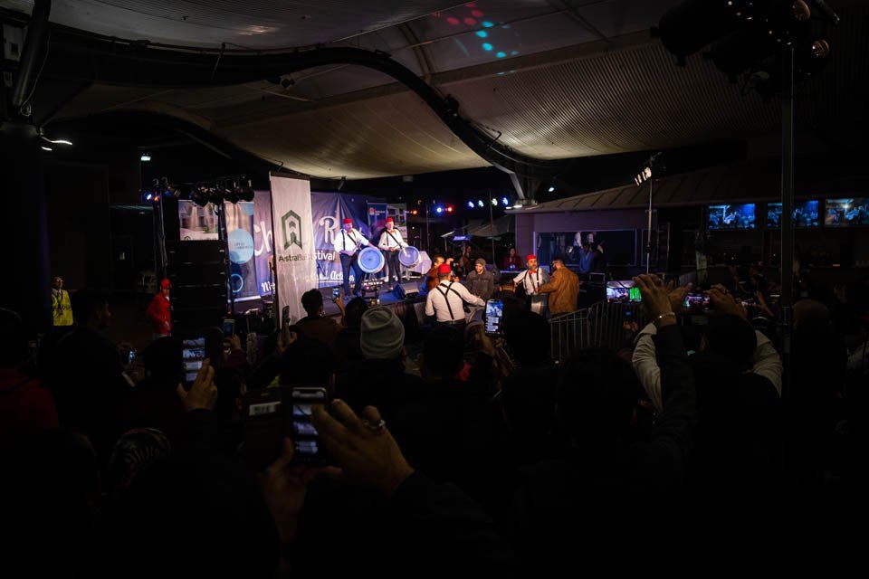 A group of people are standing in front of a stage at a concert.