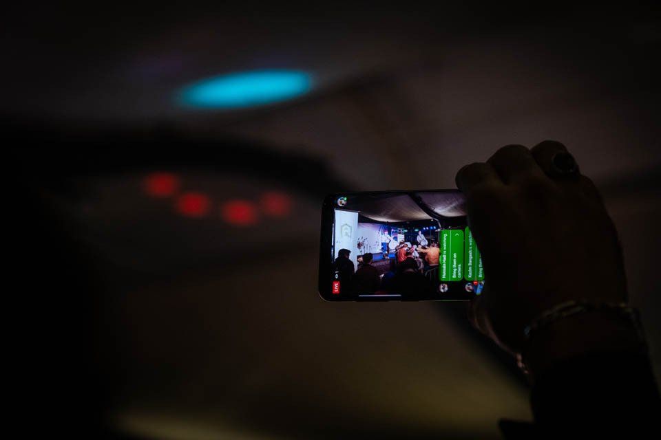 A person is taking a picture with a cell phone in the dark.