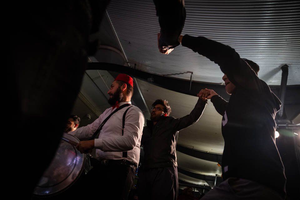 A group of men are dancing in a dark room.