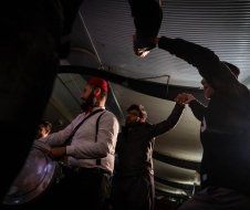 A group of men are dancing in a dark room.