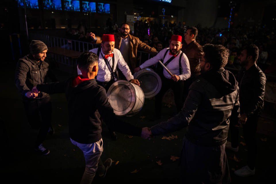 A group of men are playing drums in a dark room.