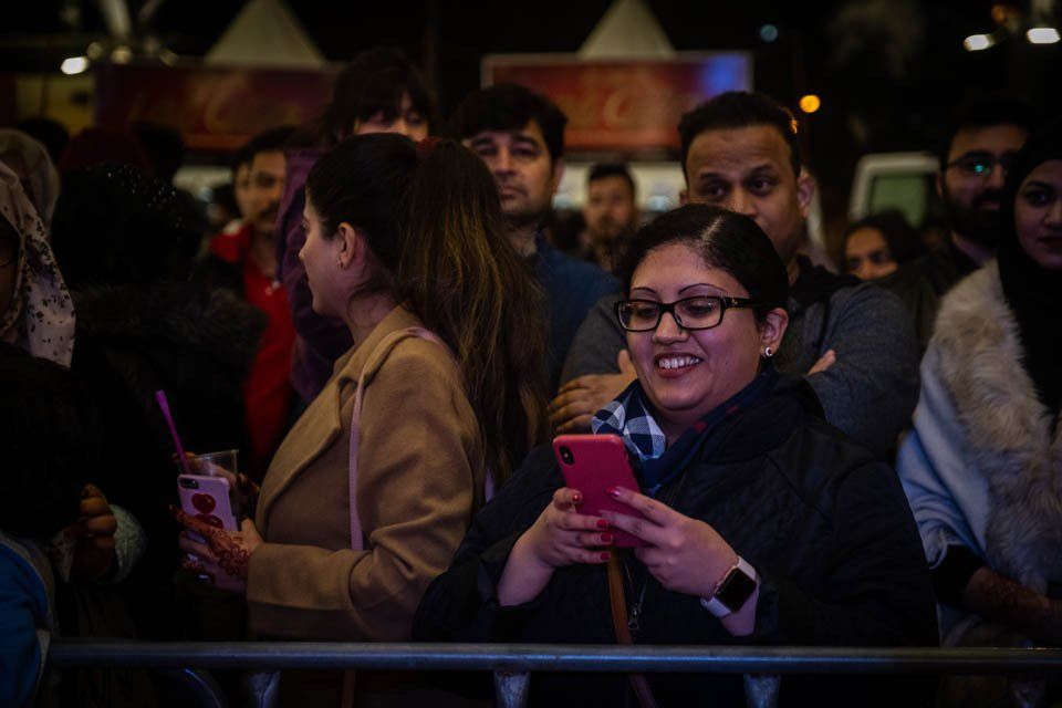 A woman is looking at her phone in a crowd of people.