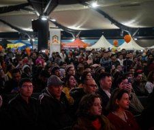 A large group of people are sitting in a room at a concert.