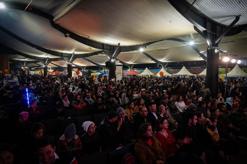 A large crowd of people are sitting in a dark room.