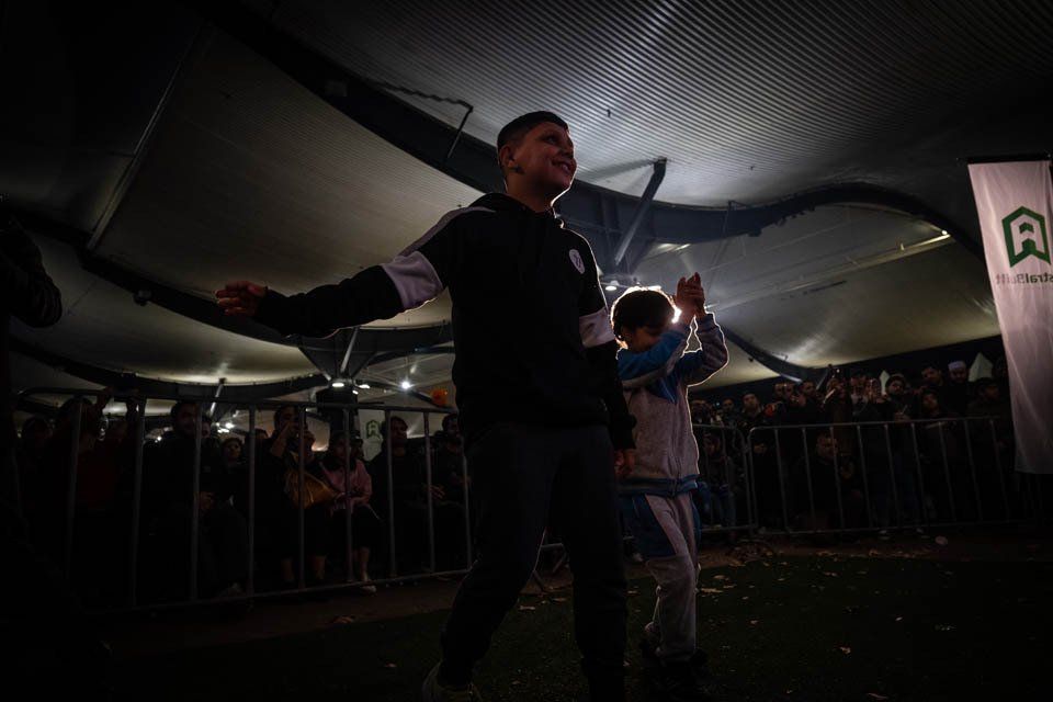 A man and a child are dancing in front of a crowd under a tent.