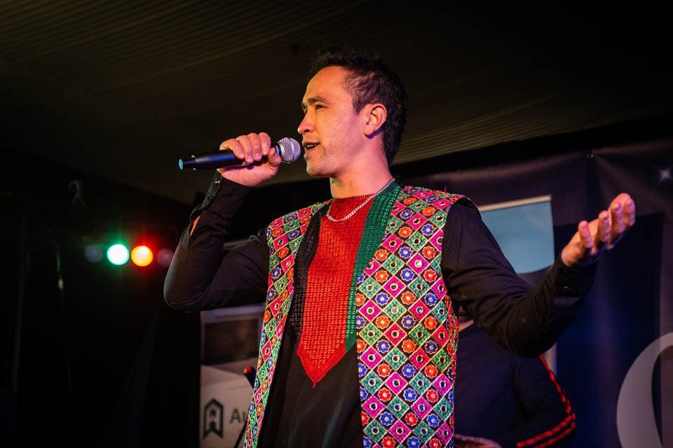 A man in a colorful vest is singing into a microphone.