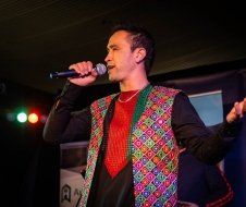 A man in a colorful vest is singing into a microphone.