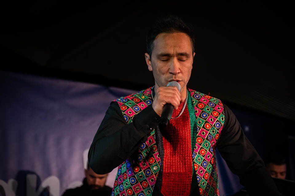 A man in a colorful vest is singing into a microphone.