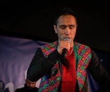 A man in a colorful vest is singing into a microphone.